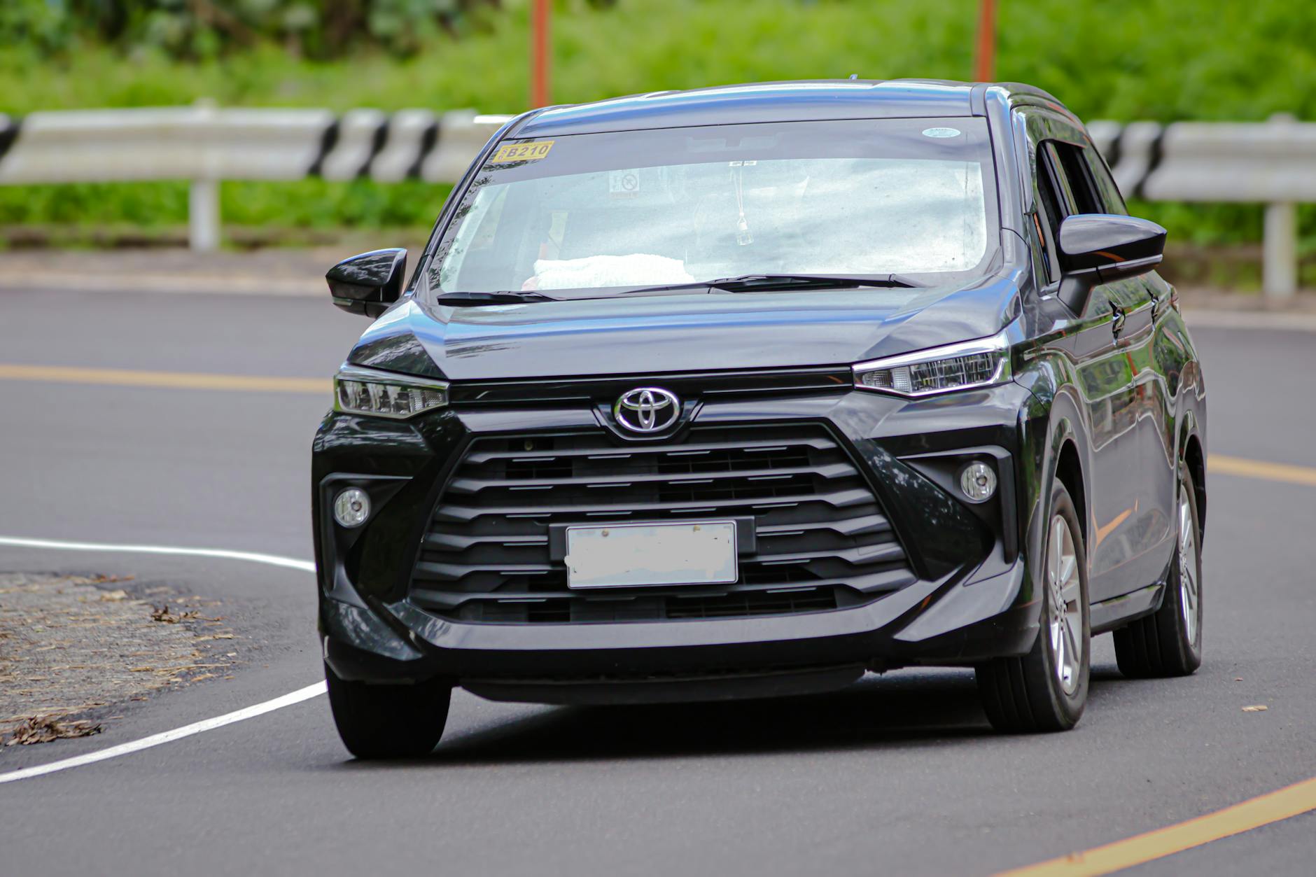 Czarny Volkswagen Caddy jedzie po miejskiej ulicy w słoneczny dzień