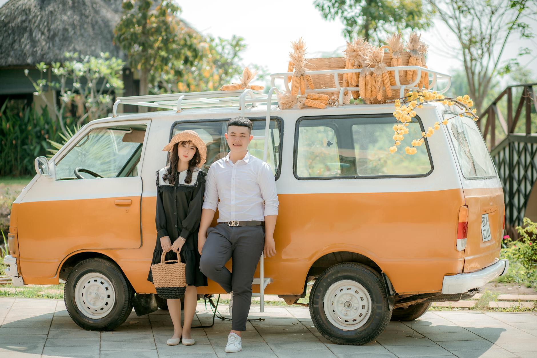 Uśmiechnięta para przy pomarańczowym klasycznym vanie załadowanym kukurydzą