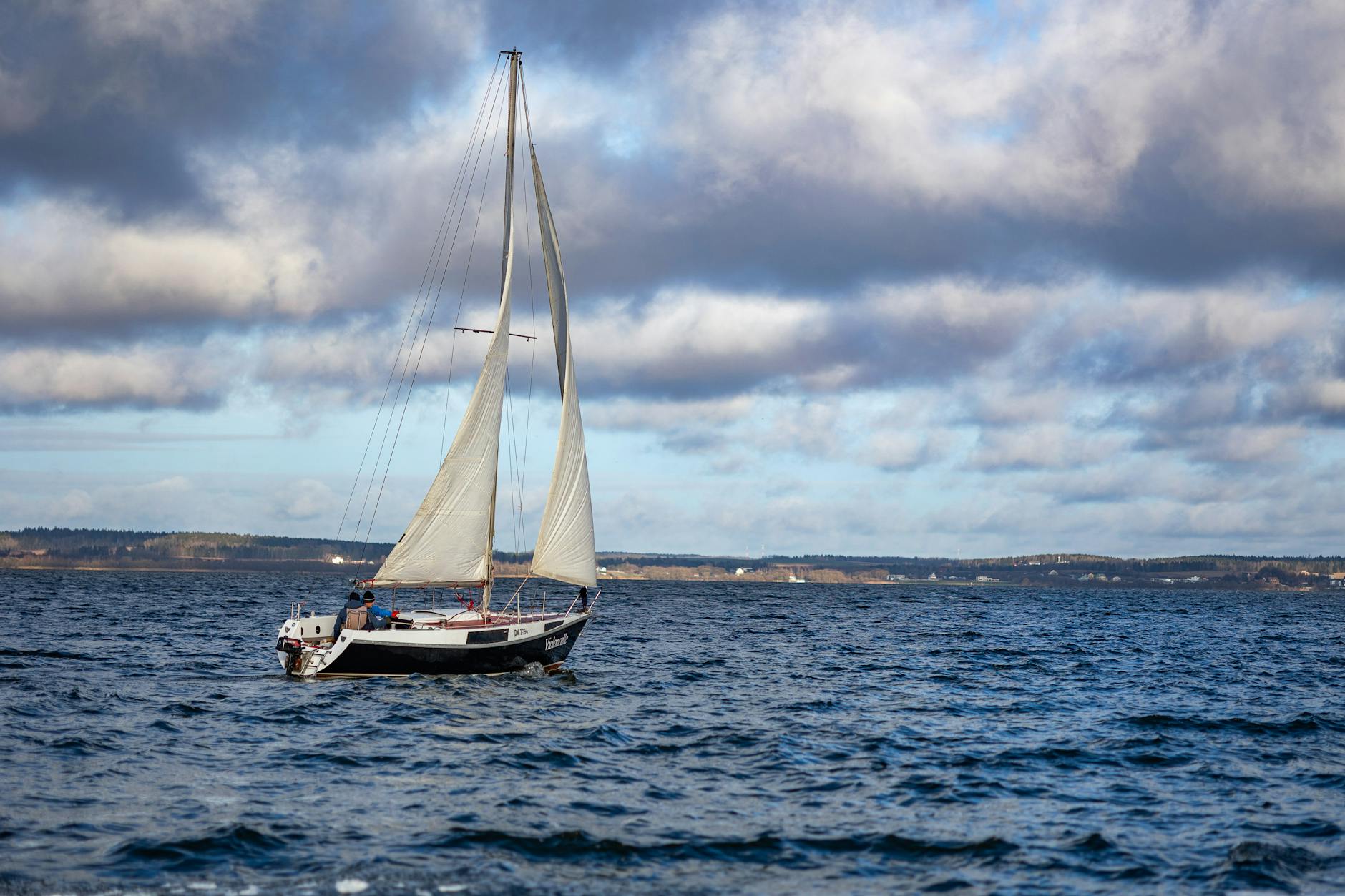 Jacht żaglowy płynie samotnie po morzu pod pochmurnym niebem