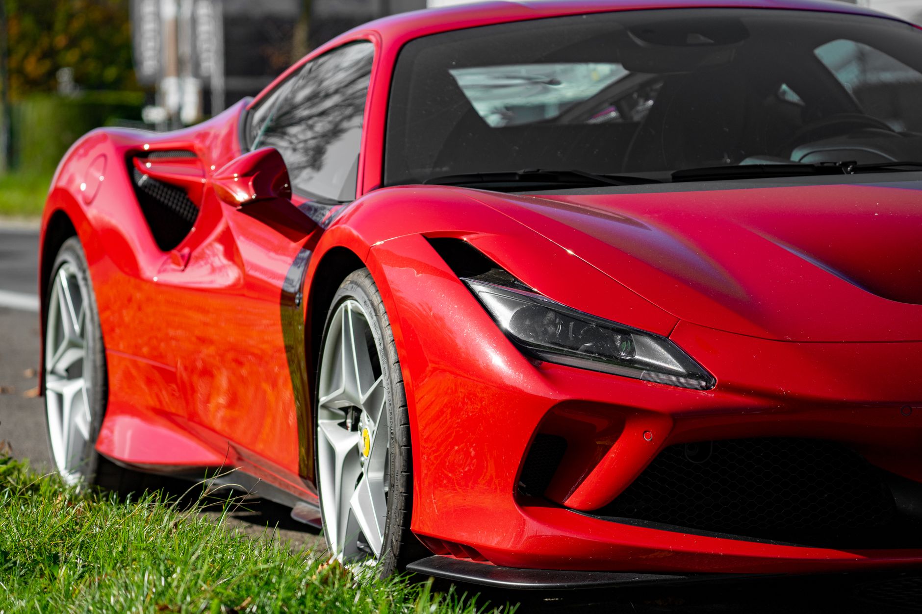 Czerwone Ferrari zaparkowane przy drodze, widok z boku
