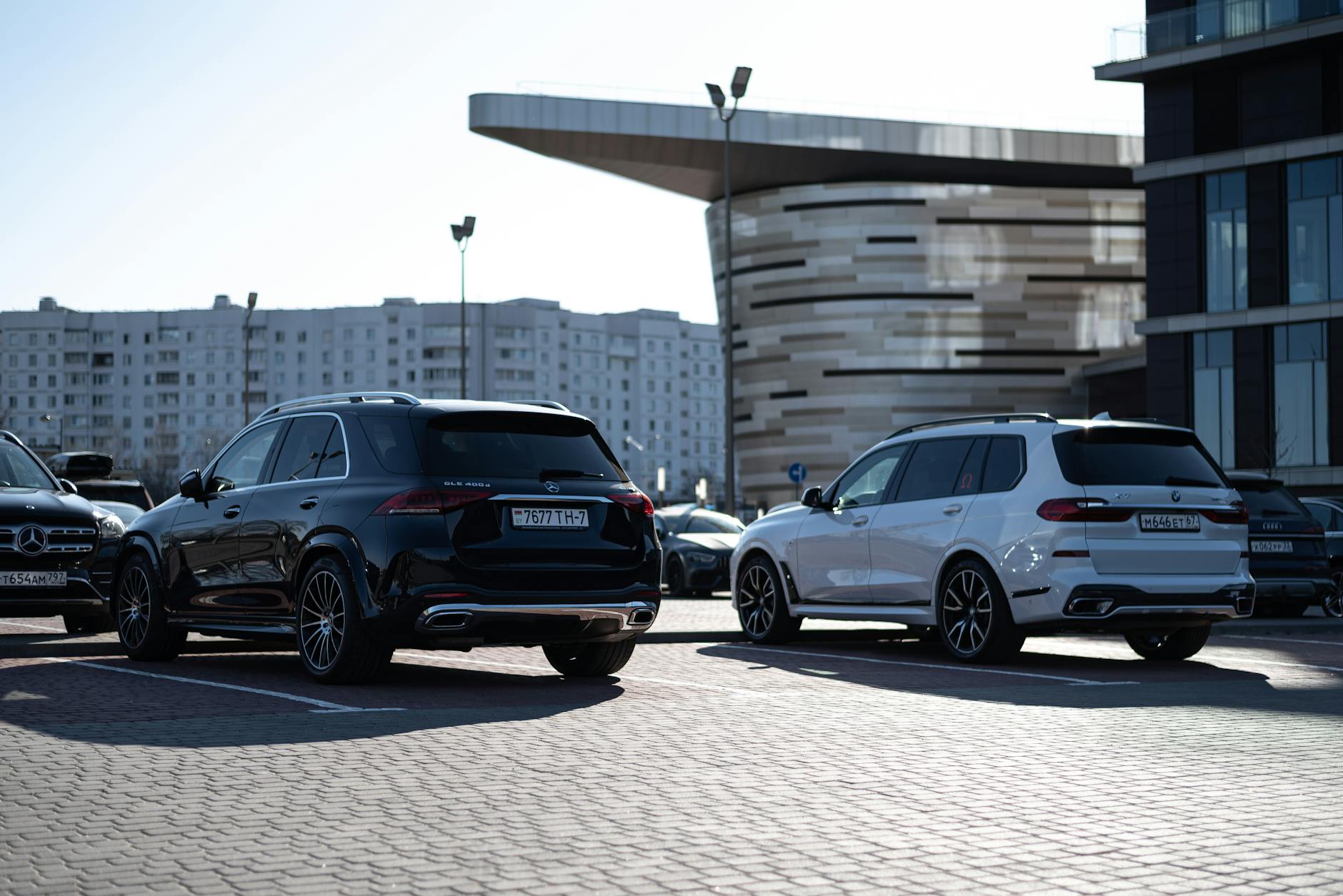 Dwa luksusowe SUV-y zaparkowane w nowoczesnej miejskiej zabudowie