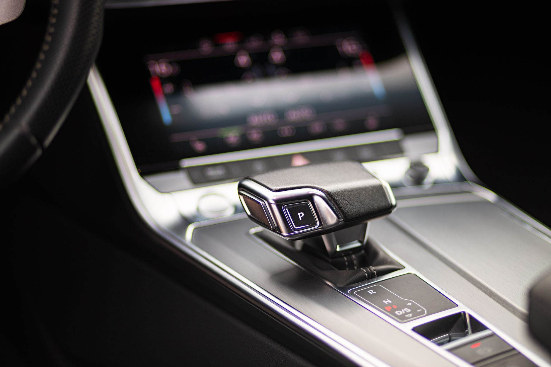 Zbliżenie na dźwignię zmiany biegów i panel sterowania w aucie Tesla