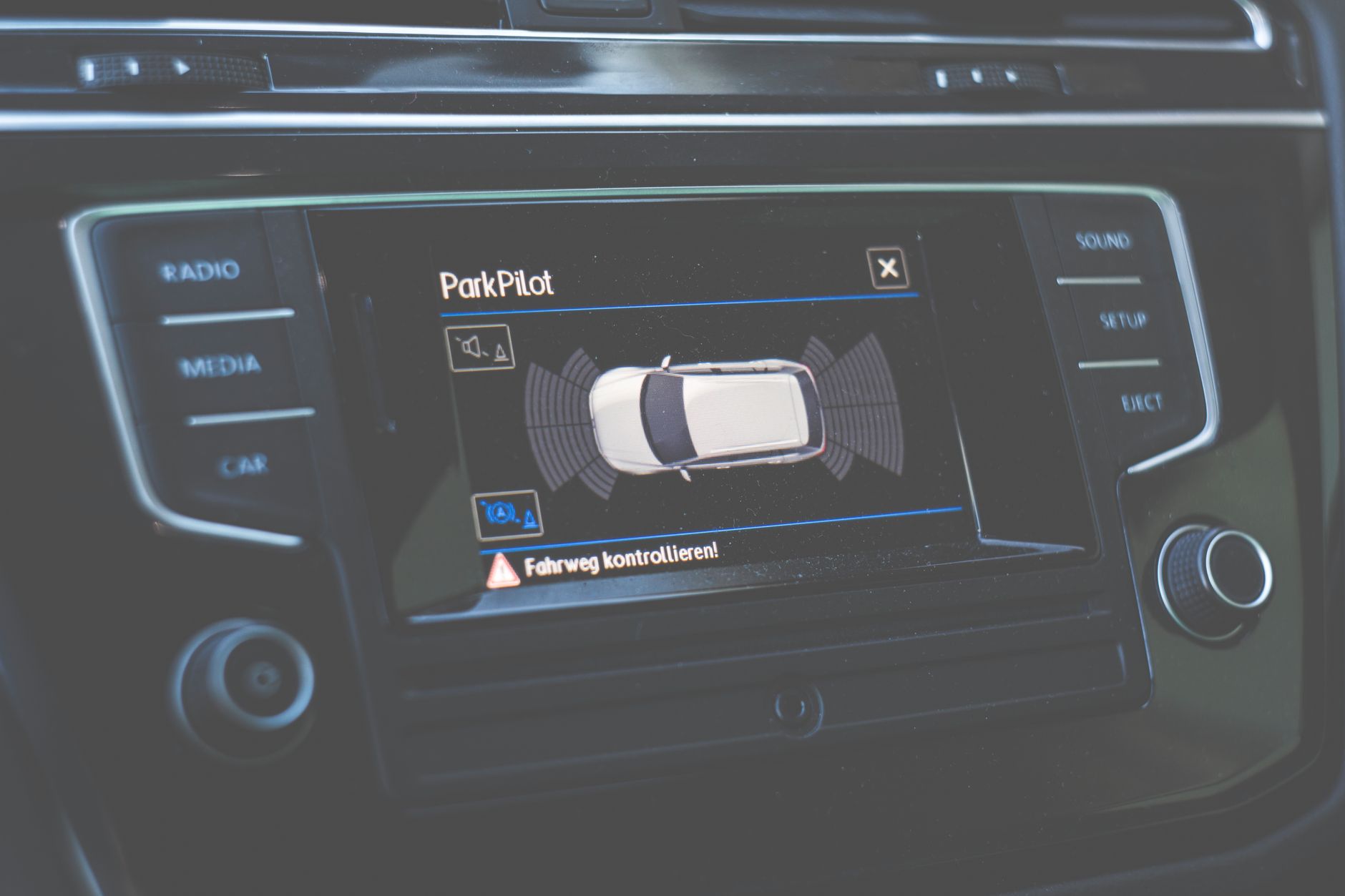 Zbliżenie na ekran ParkPilot na desce rozdzielczej samochodu