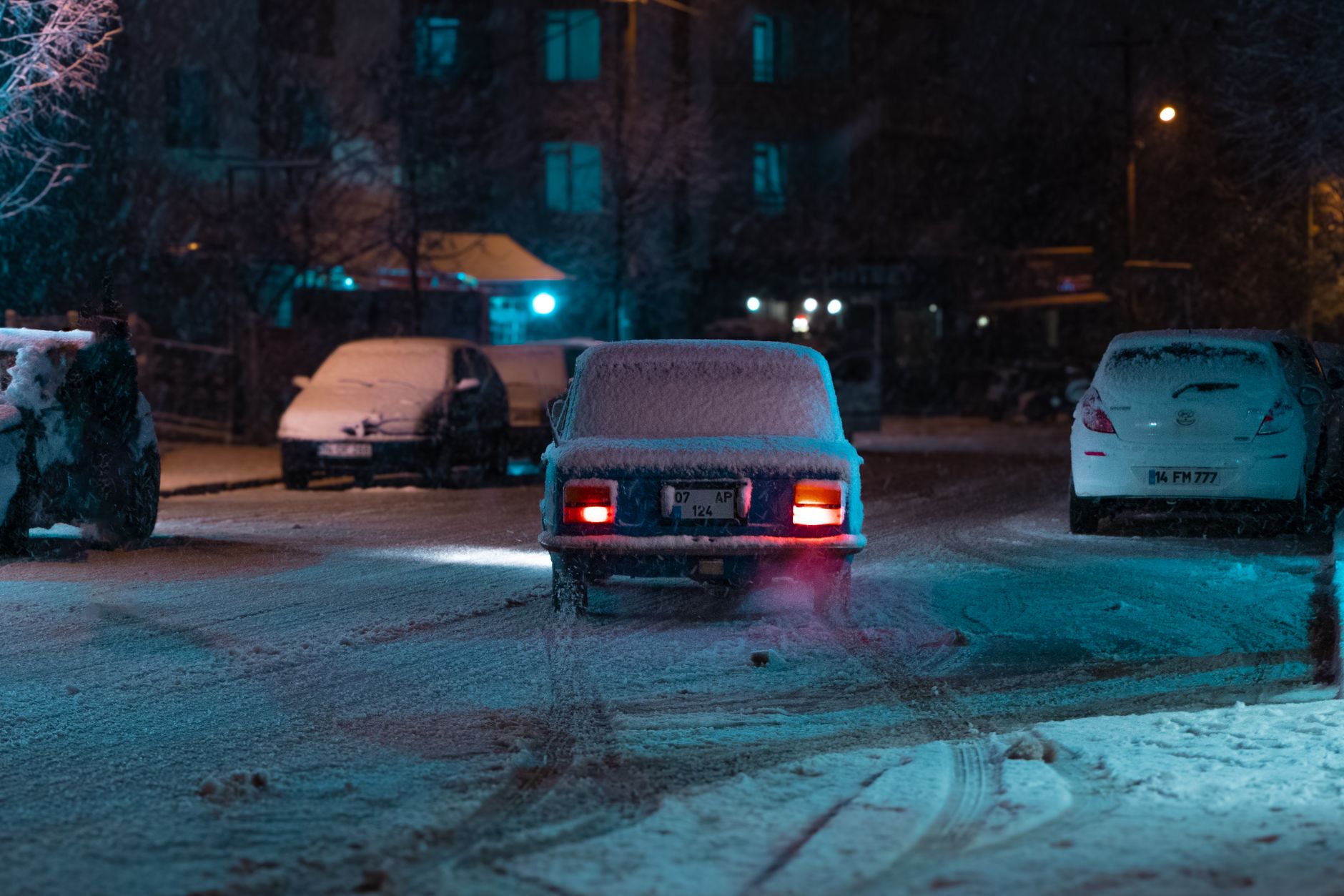Zabytkowy Cadillac jedzie nocą po zaśnieżonej ulicy miasta